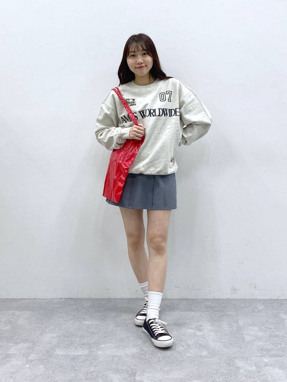 グレー系のスカート、レッド系のトートバッグ、ベージュ系のスウェットを着用したレディースの春コーディネートの1枚目の写真