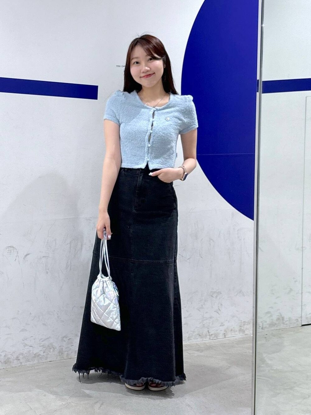 ブラック系のデニムスカート、シルバー系のショルダーバッグ、ブルー系のカーディガン/ボレロを着用したレディースの夏コーディネートの1枚目の写真