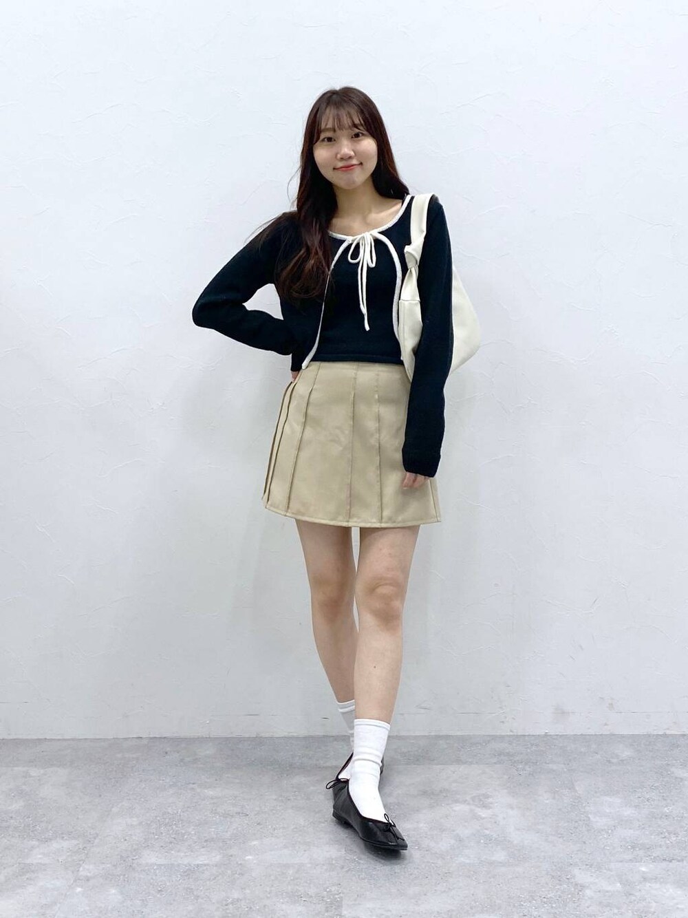 ベージュ系のスカート、ブラック系のカーディガン/ボレロを着用したレディースの春コーディネートの1枚目の写真