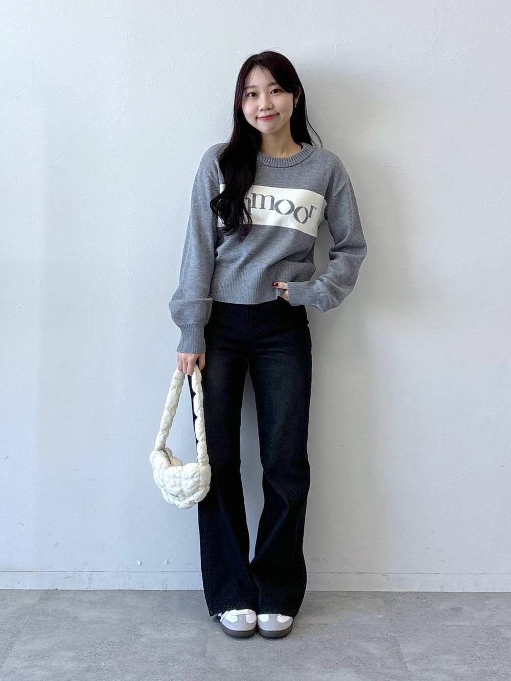 ホワイト系のショルダーバッグ、ブラック系のデニムパンツ、グレー系のニット/セーターを着用したレディースの冬コーディネートの1枚目の写真