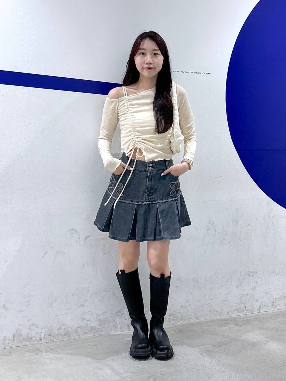 ホワイト系のショルダーバッグ、ベージュ系のTシャツ/カットソー、ブルー系のデニムスカートを着用したレディースの秋コーディネートの1枚目の写真