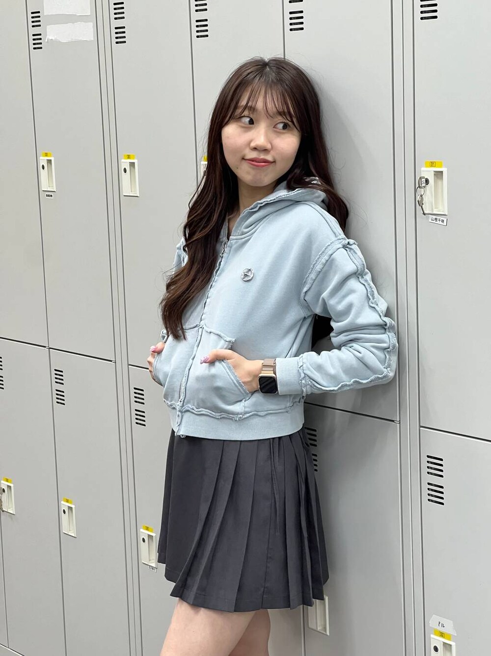 グレー系のスカート、ブルー系のパーカーを着用したレディースの春コーディネートの1枚目の写真