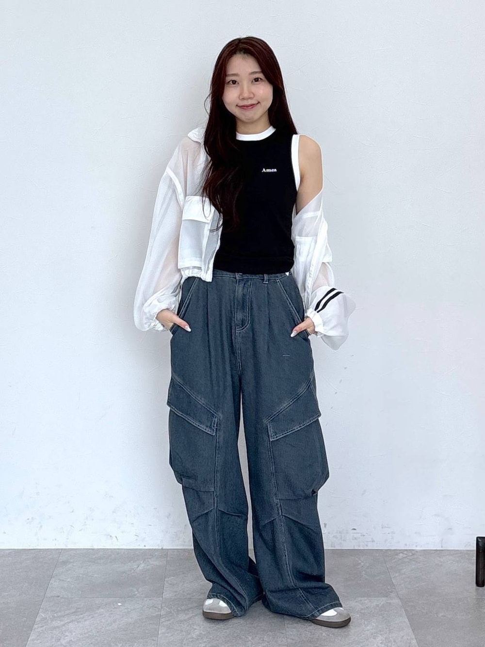 ブルー系のカーゴパンツ、ブラック系のタンクトップ、ホワイト系のブルゾンを着用したレディースの春コーディネートの1枚目の写真