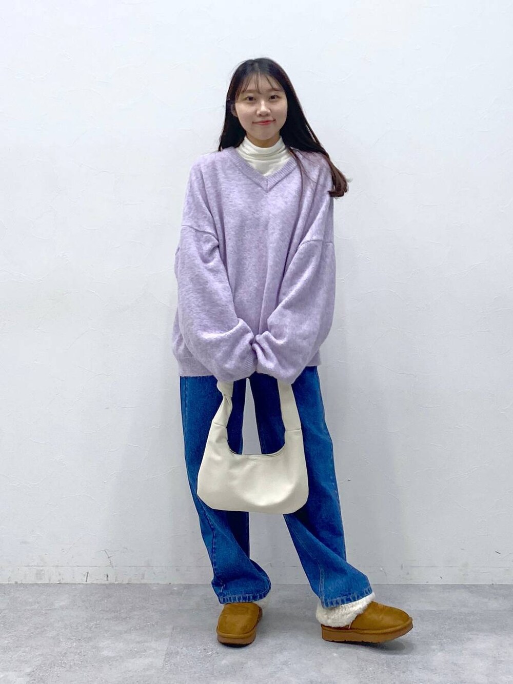 ブルー系のデニムパンツ、ベージュ系のTシャツ/カットソー、パープル系のニット/セーターを着用したレディースの冬コーディネートの1枚目の写真