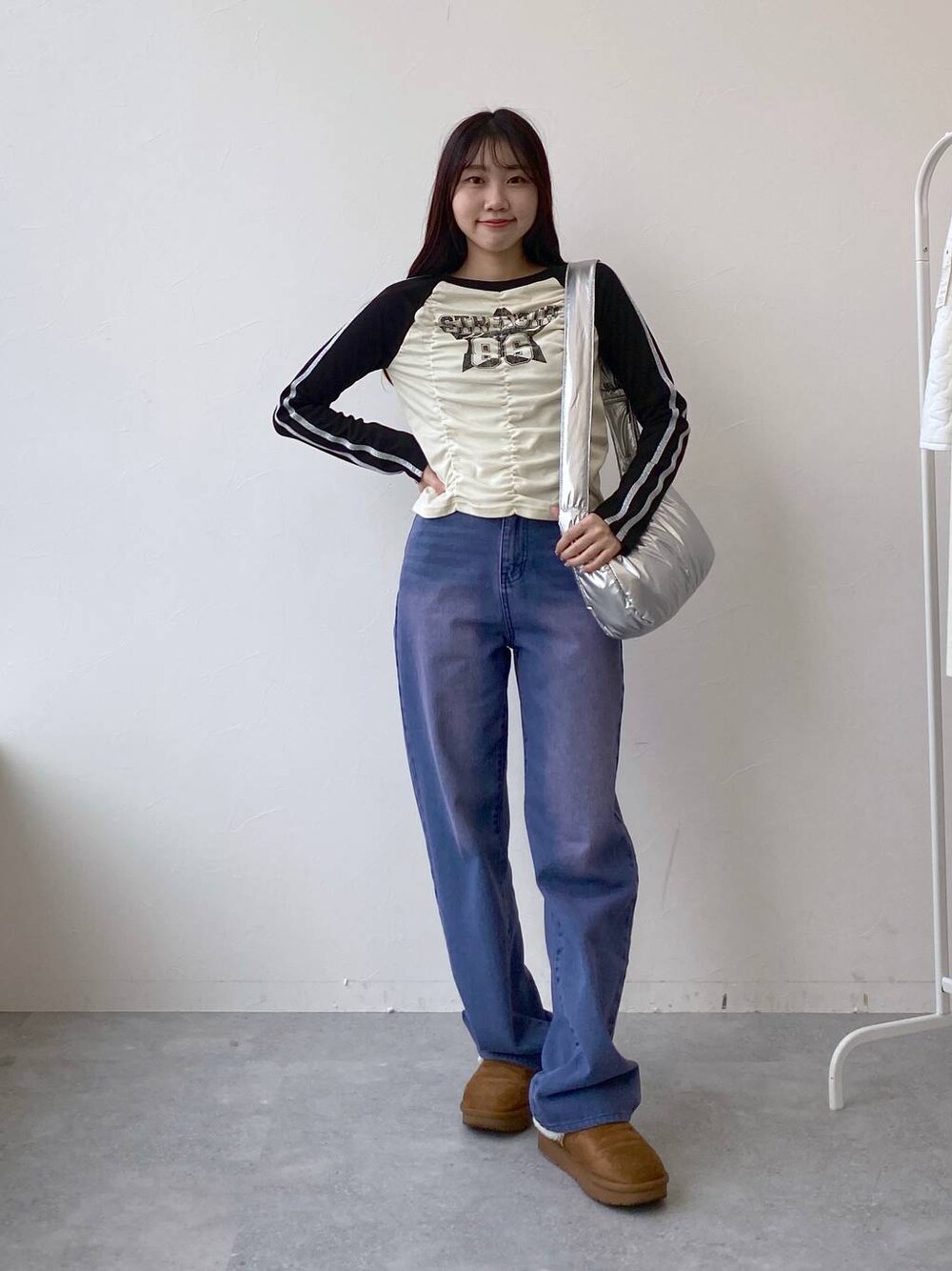 パープル系のデニムパンツ、その他のショルダーバッグ、ベージュ系のTシャツ/カットソーを着用したレディースの冬コーディネートの1枚目の写真