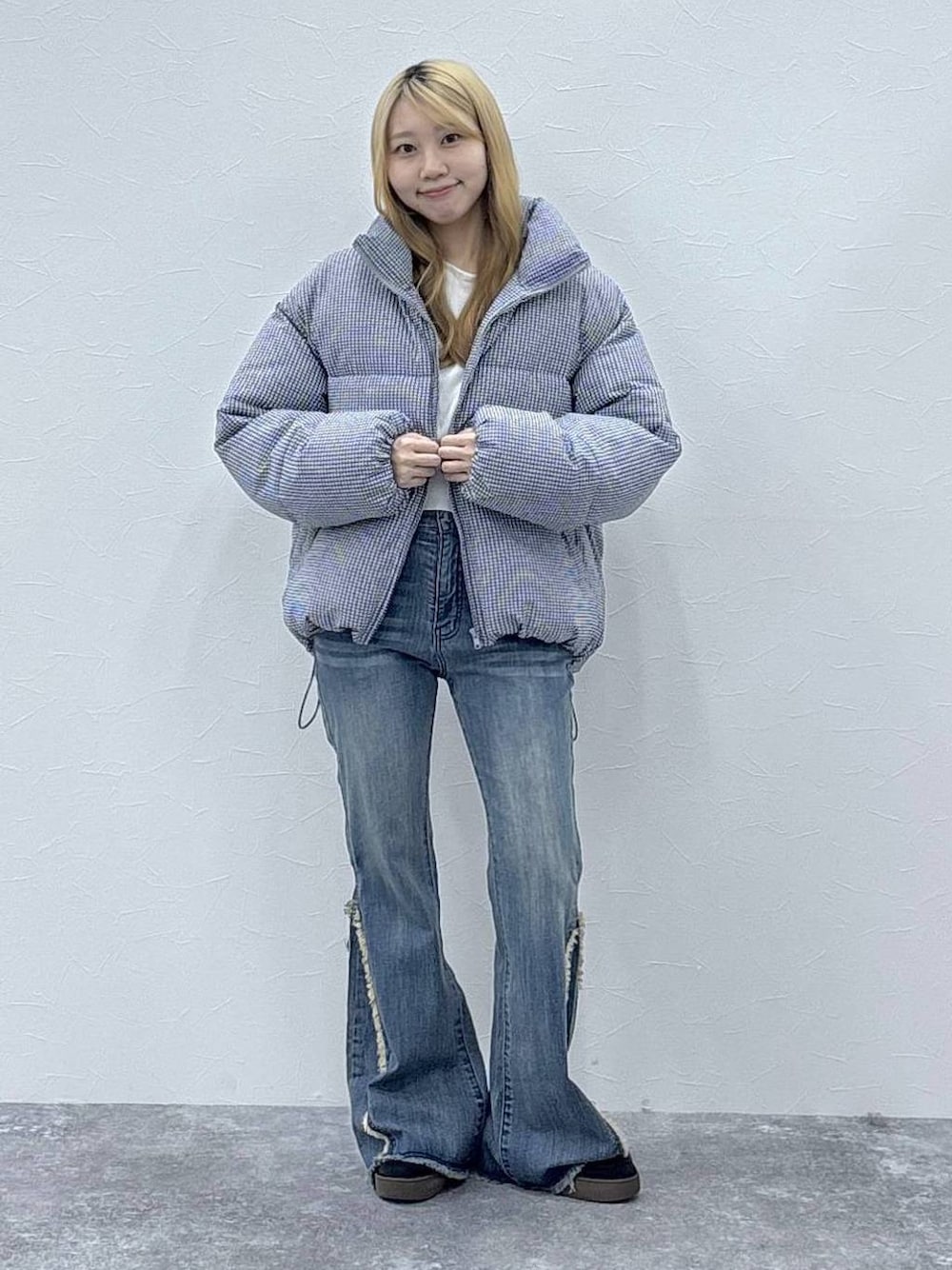 ブラック系のダウンジャケット/コート、ホワイト系のニット/セーター、ブラック系のデニムパンツを着用したレディースの秋コーディネートの1枚目の写真