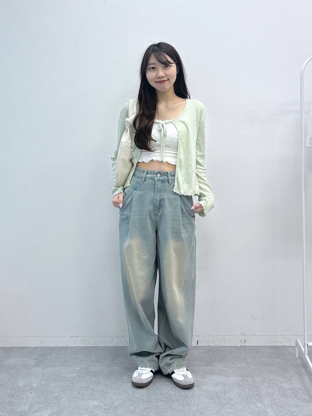 ブルー系のデニムパンツ、ベージュ系のチューブトップ、グリーン系のカーディガン/ボレロを着用したレディースの春コーディネートの1枚目の写真