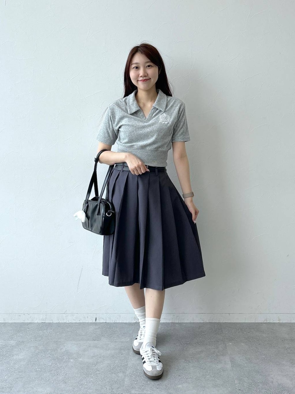 ブラック系のハンドバッグ、グレー系のスカート、グレー系のTシャツ/カットソーを着用したレディースの夏コーディネートの1枚目の写真