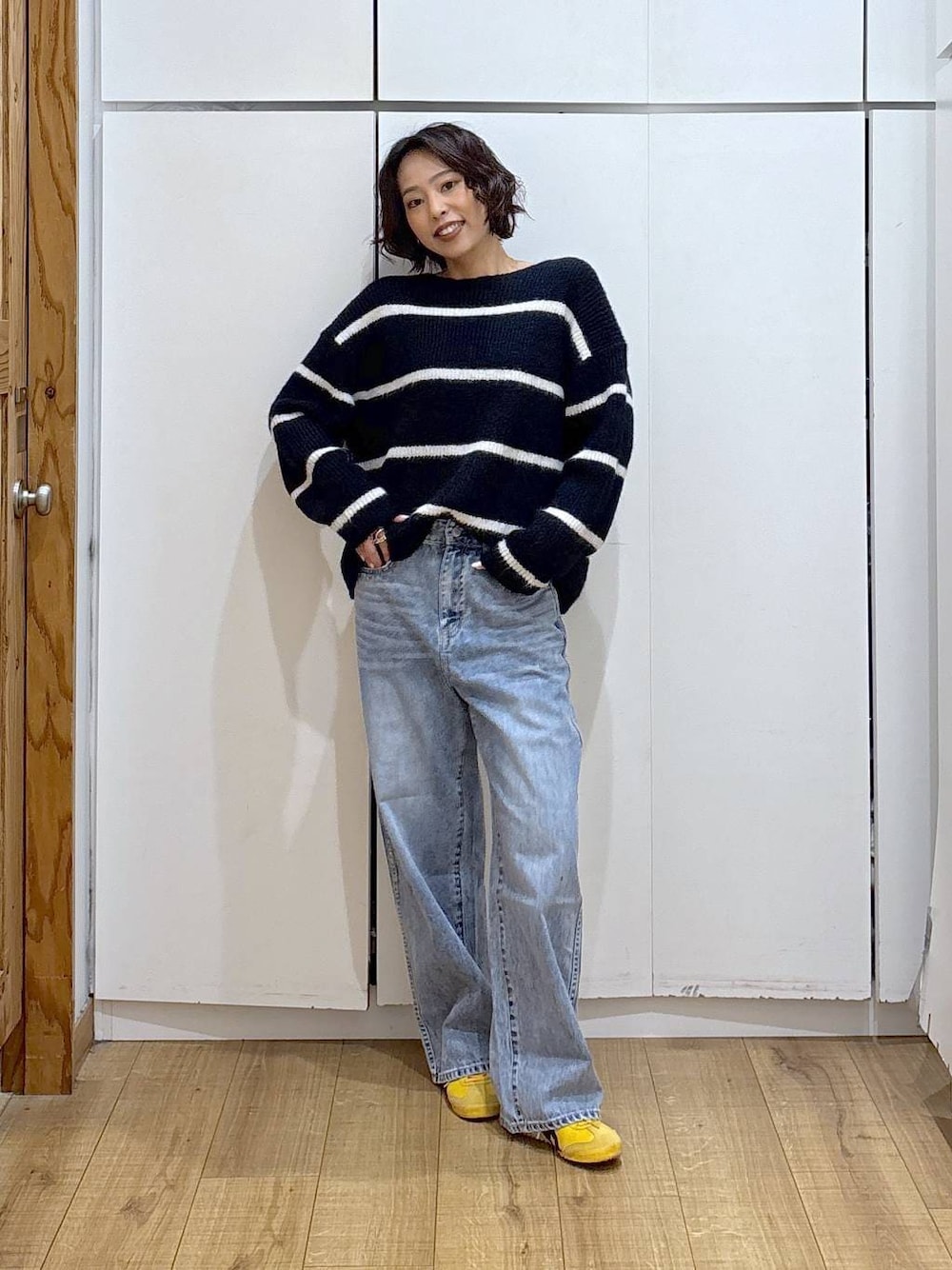 ブルー系のデニムパンツ、ブルー系のニット/セーター、ゴールド系のピアス(両耳用)を着用したレディースの冬コーディネートの1枚目の写真