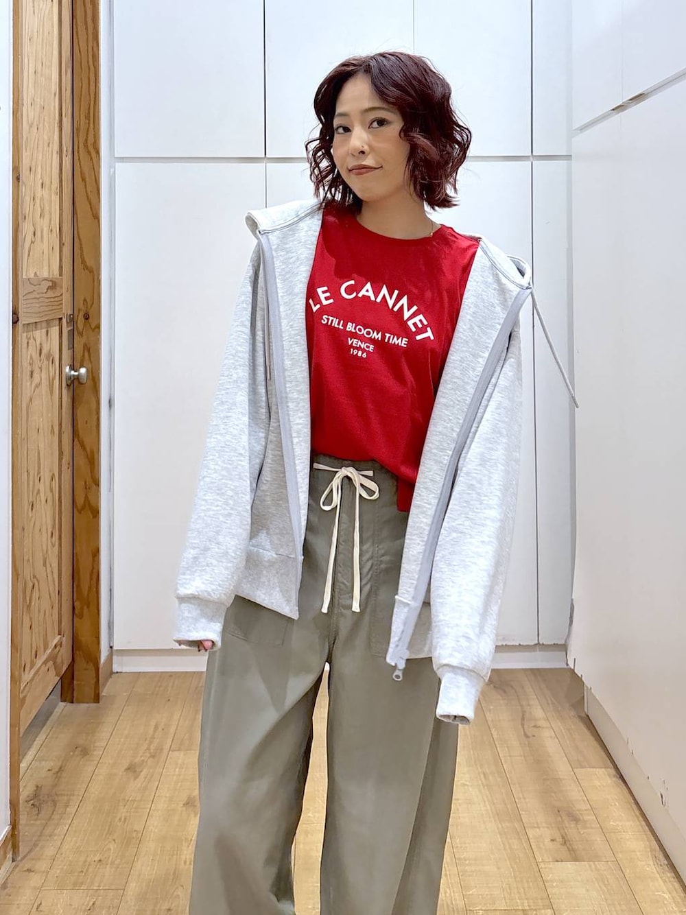レッド系のTシャツ/カットソー、グリーン系のその他パンツ、グレー系のパーカーを着用したレディースの春コーディネートの1枚目の写真