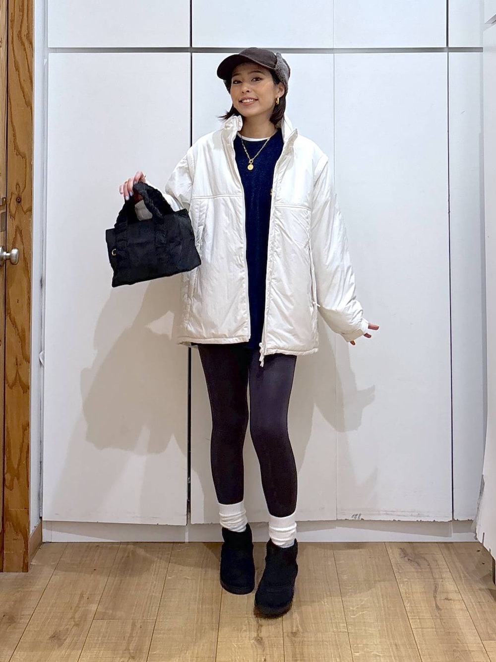 ブラック系のショルダーバッグ、ベージュ系のブルゾン、ホワイト系のTシャツ/カットソーを着用したレディースの冬コーディネートの1枚目の写真