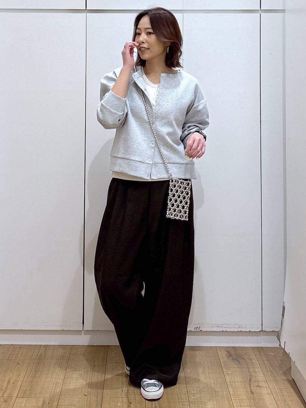 グレー系のカーディガン/ボレロ、ブラウン系のその他パンツ、ホワイト系のタンクトップを着用したレディースの春コーディネートの1枚目の写真