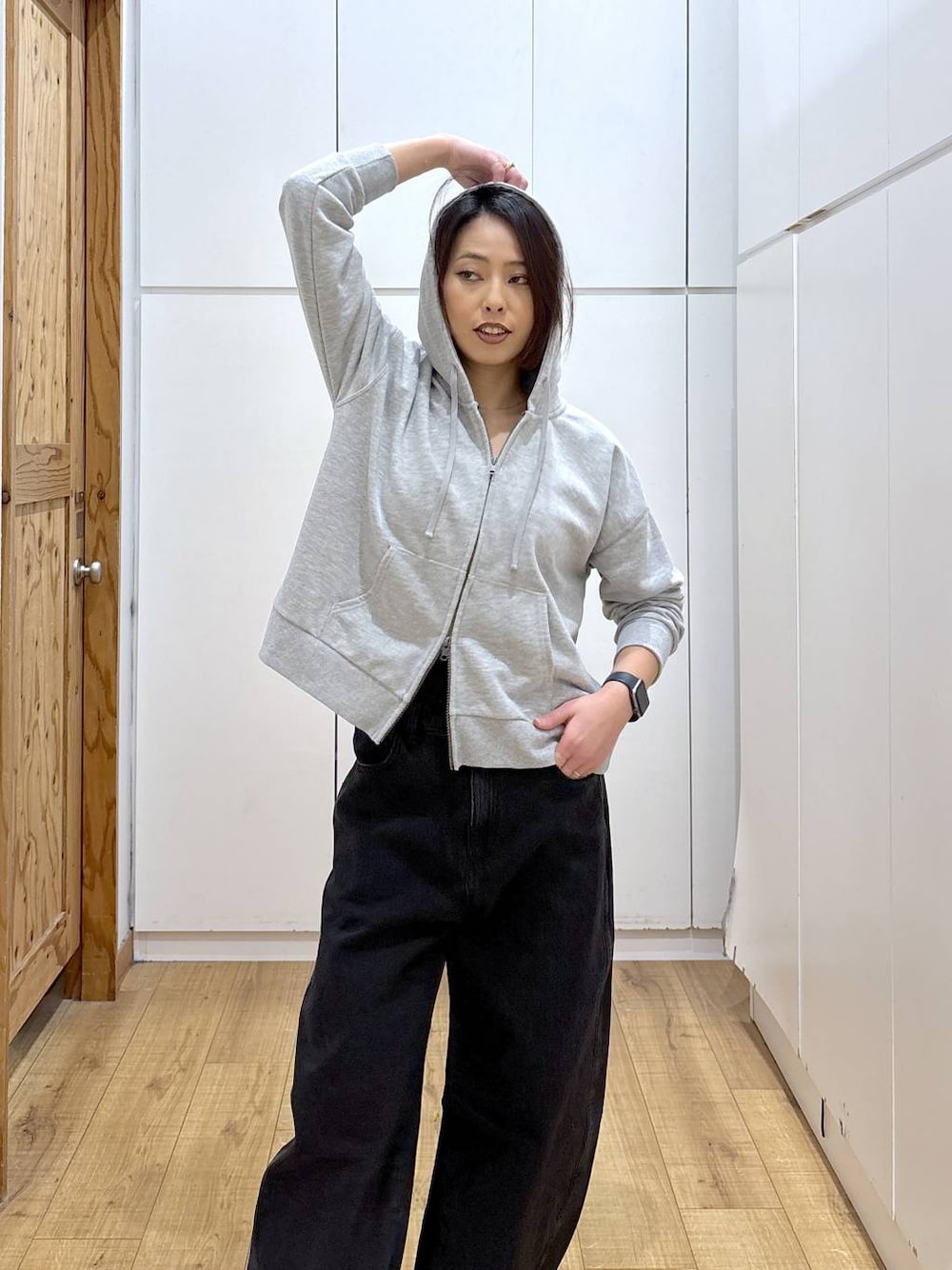 ブラック系のスニーカー、ブラック系のデニムパンツ、グレー系のパーカーを着用したレディースの冬コーディネートの1枚目の写真