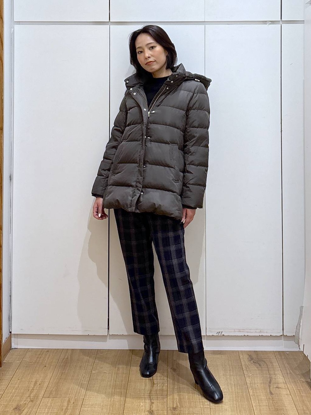 ブラウン系のダウンジャケット/コート、ブラック系のニット/セーター、ブルー系のその他パンツを着用したレディースの秋コーディネートの1枚目の写真