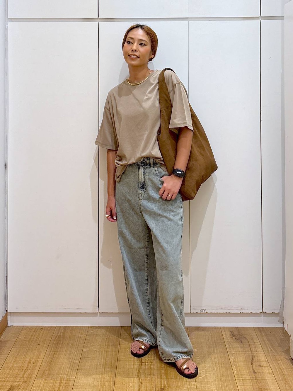 ブラウン系のサンダル、ベージュ系のTシャツ/カットソー、ブルー系のデニムパンツを着用したレディースの秋コーディネートの1枚目の写真