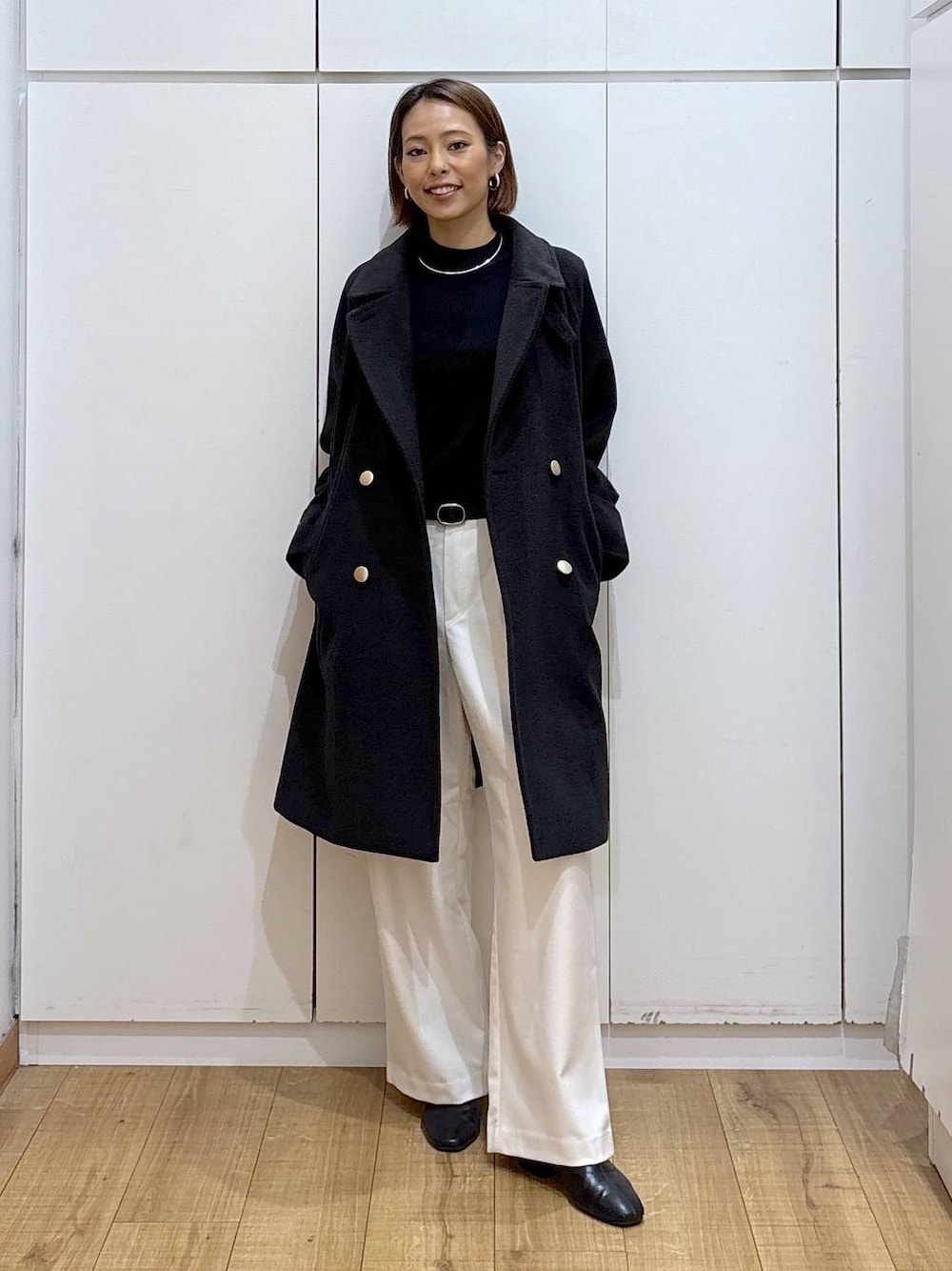 ブラック系のチェスターコート、ブラック系のニット/セーター、グレー系のその他パンツを着用したレディースの秋コーディネートの1枚目の写真