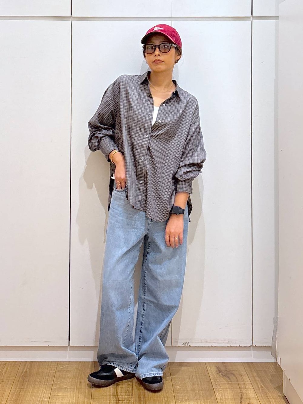 ブラック系のスニーカー、ホワイト系のキャミソール、ブルー系のデニムパンツを着用したレディースの秋コーディネートの1枚目の写真