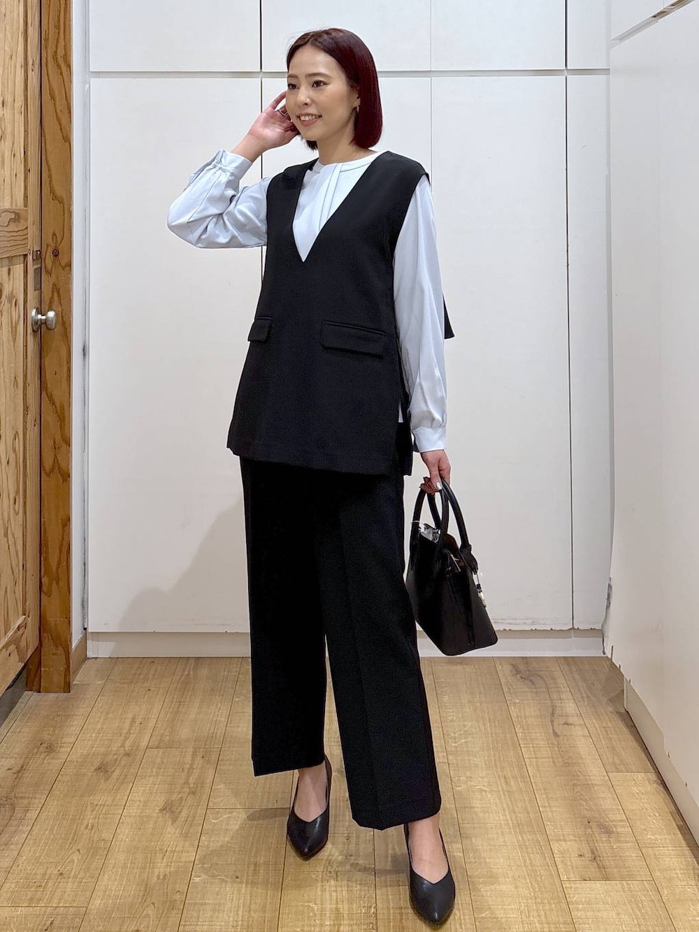 ブラック系のショルダーバッグ、ブラック系のパンプス、ブルー系のシャツ/ブラウスを着用したレディースの春コーディネートの1枚目の写真