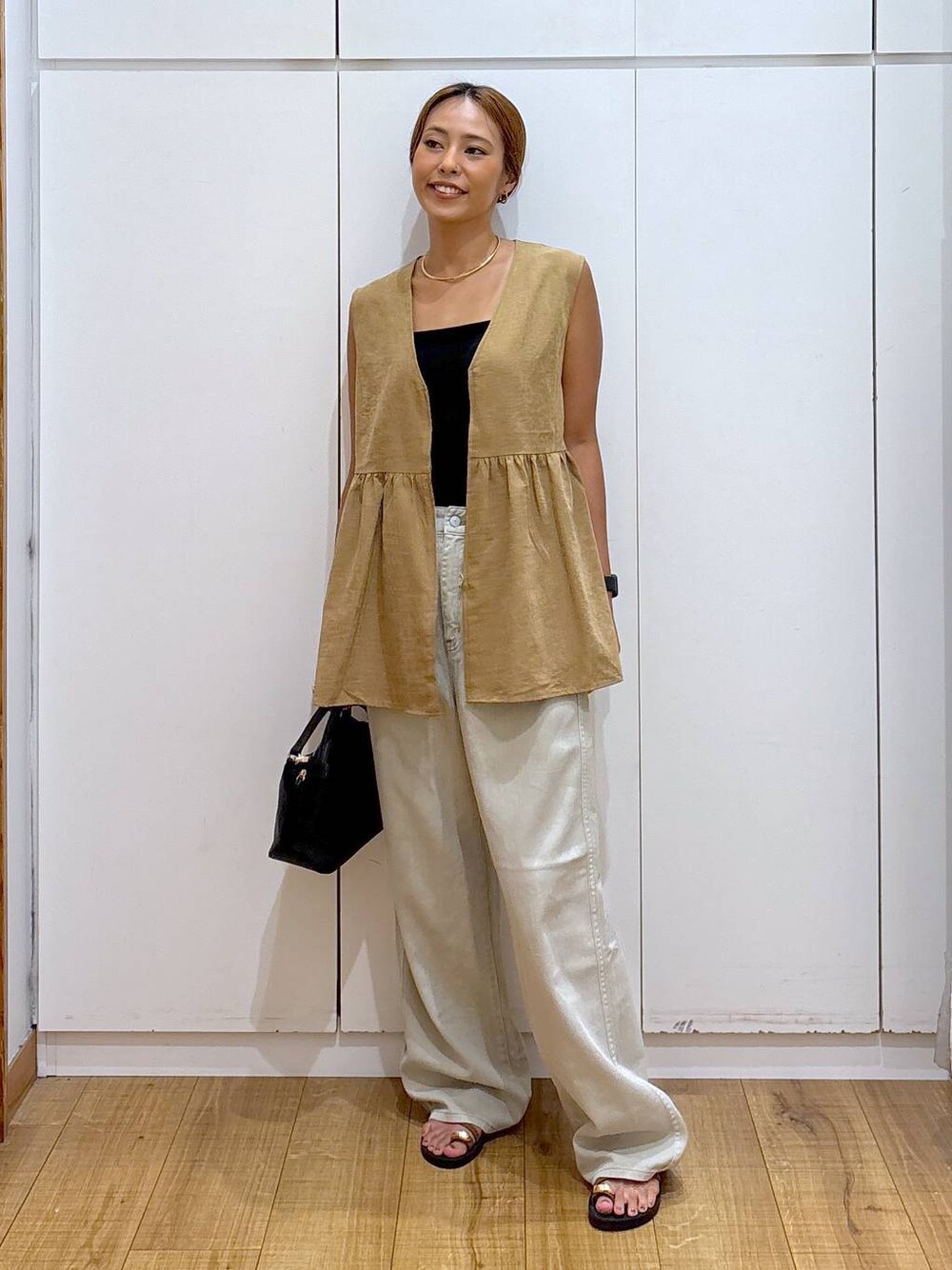 ブラック系のショルダーバッグ、ブラック系のキャミソール、ブラウン系のサンダルを着用したレディースの秋コーディネートの1枚目の写真