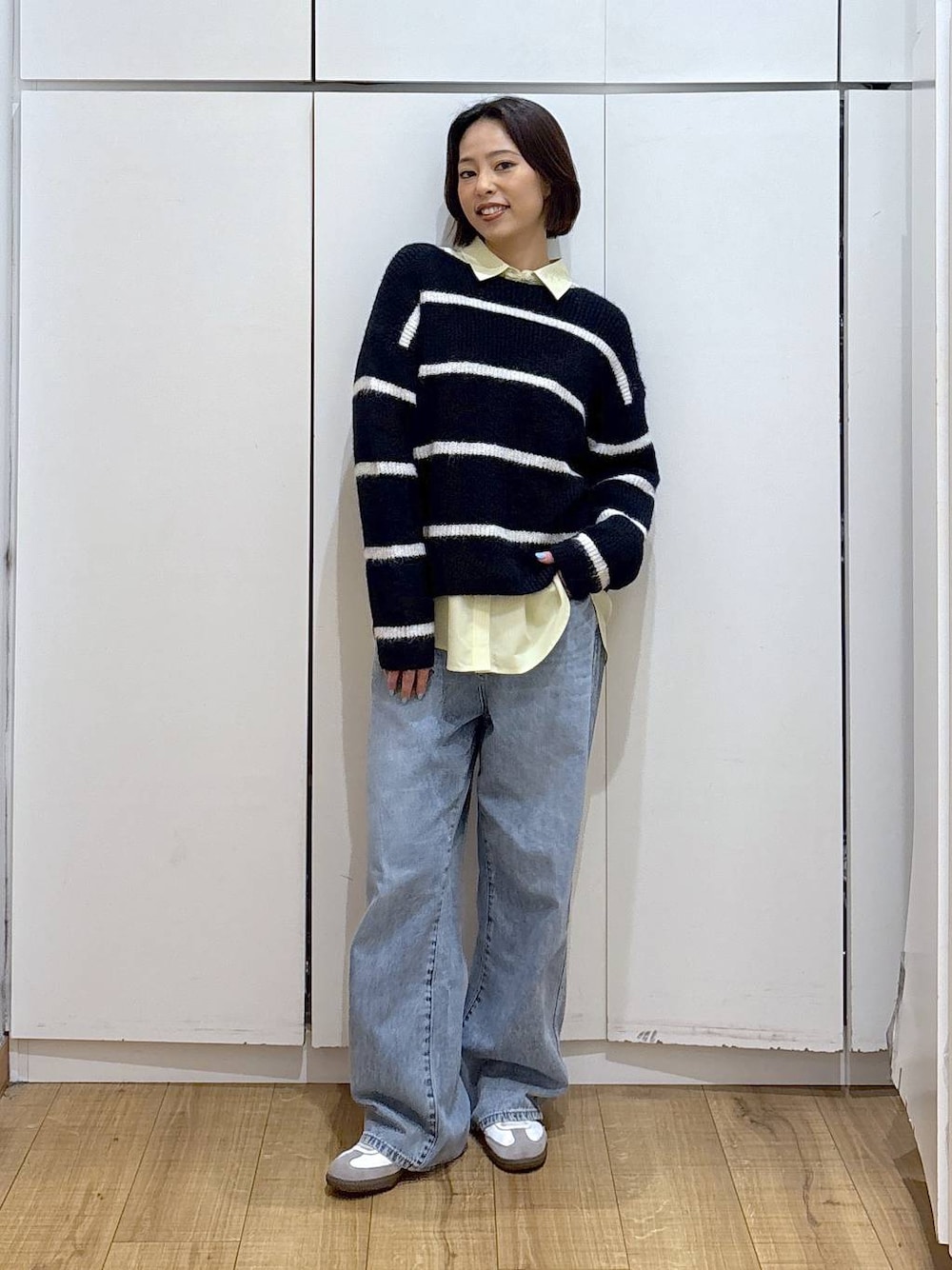 ブルー系のデニムパンツ、イエロー系のシャツ/ブラウス、ブルー系のニット/セーターを着用したレディースの冬コーディネートの1枚目の写真