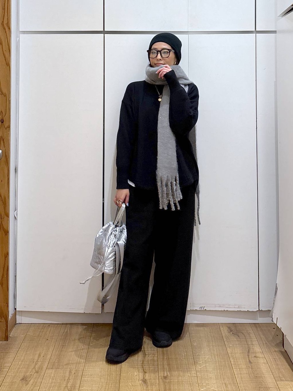 ブラック系のニット/セーター、シルバー系のハンドバッグ、ホワイト系のTシャツ/カットソーを着用したレディースの冬コーディネートの1枚目の写真