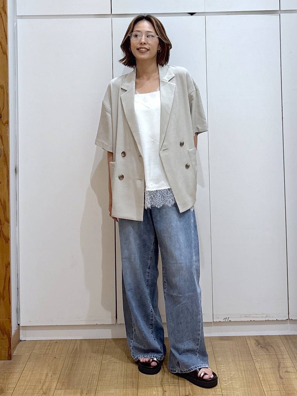 ホワイト系のキャミソール、ブルー系のデニムパンツ、ベージュ系のテーラードジャケットを着用したレディースの春コーディネートの1枚目の写真
