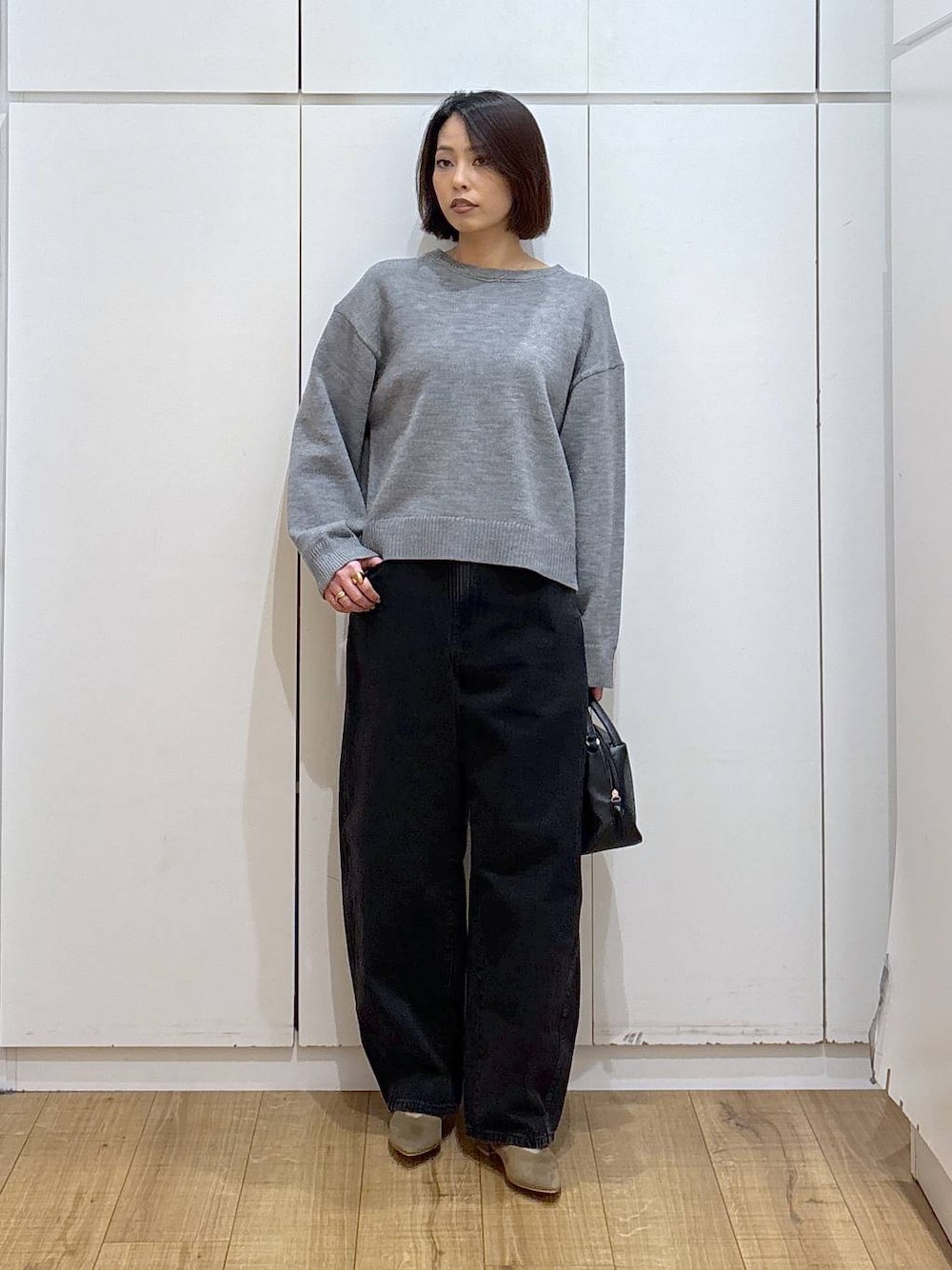 ブラック系のショルダーバッグ、ベージュ系のパンプス、ブラック系のデニムパンツを着用したレディースの冬コーディネートの1枚目の写真