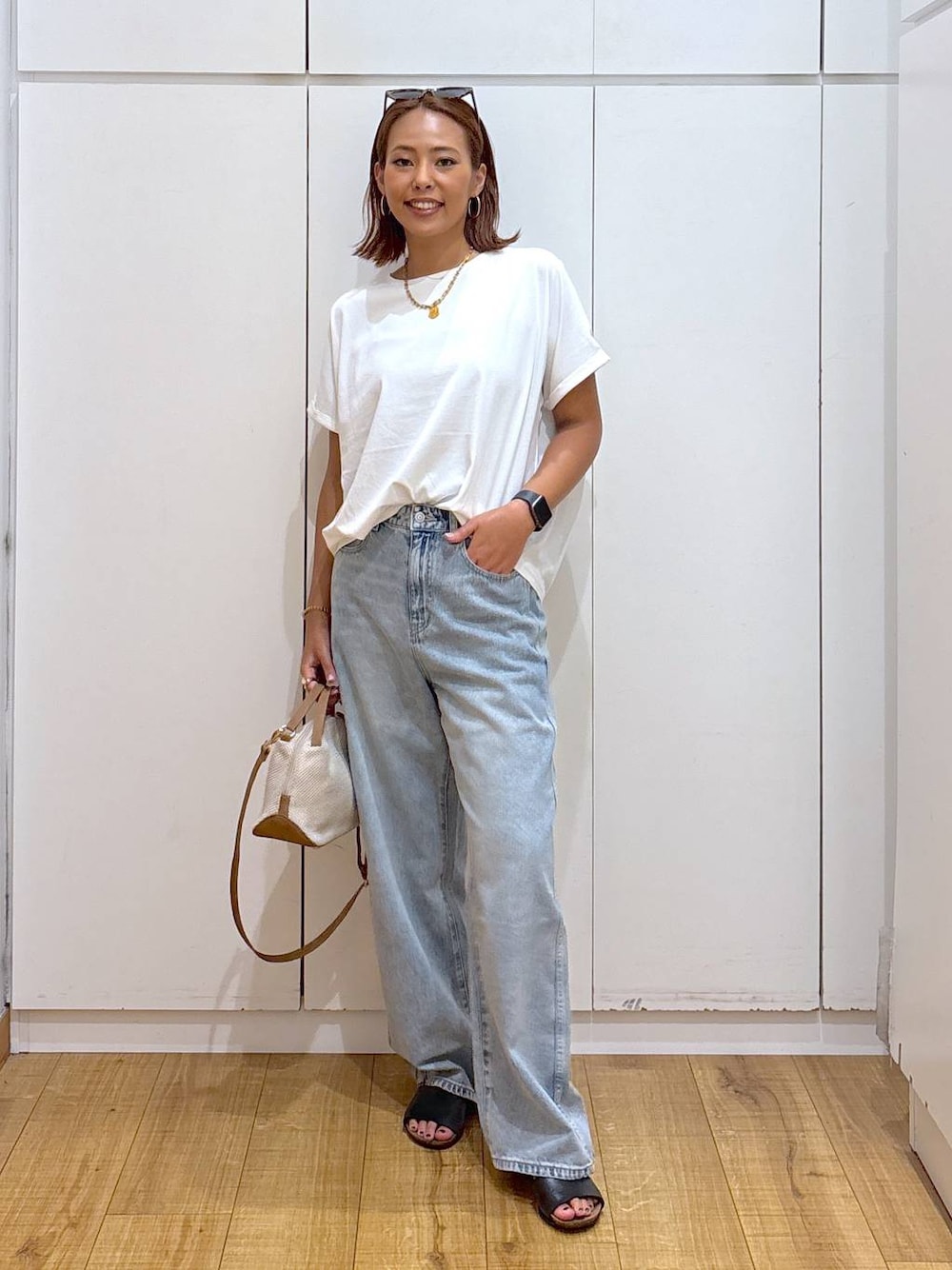 ブルー系のデニムパンツ、ホワイト系のショルダーバッグ、ホワイト系のTシャツ/カットソーを着用したレディースの夏コーディネートの1枚目の写真