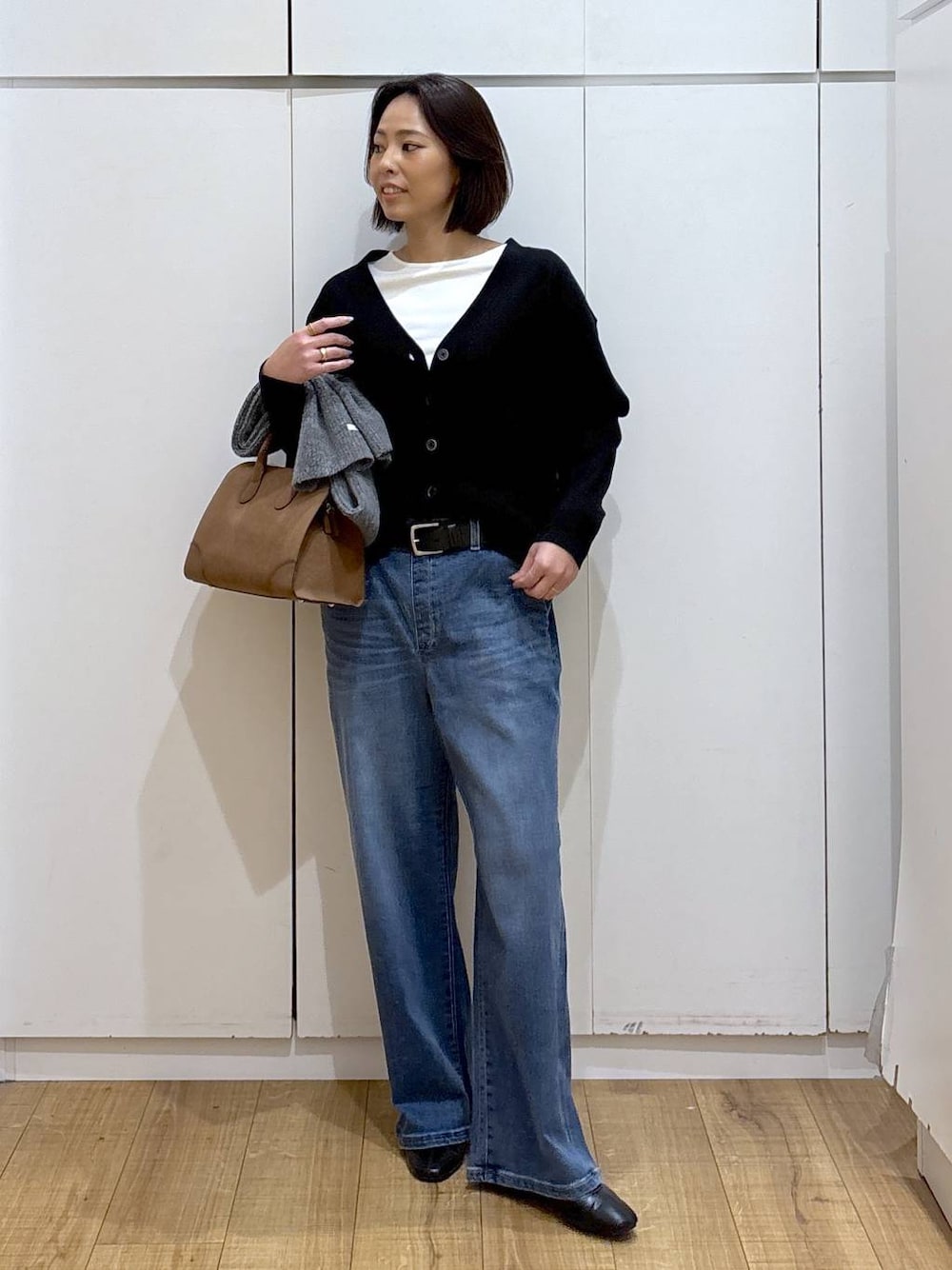 ブラック系のカーディガン/ボレロ、ベージュ系のショルダーバッグ、ブラック系のブーツを着用したレディースの秋コーディネートの1枚目の写真