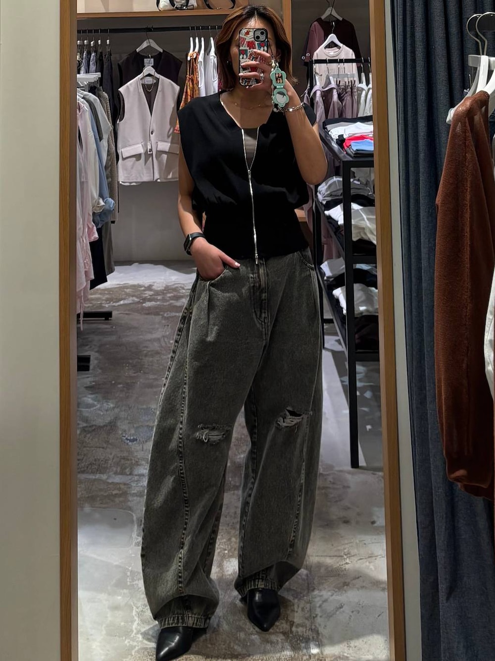 グレー系のデニムパンツ、ブラック系のベストを着用したレディースの春コーディネートの1枚目の写真