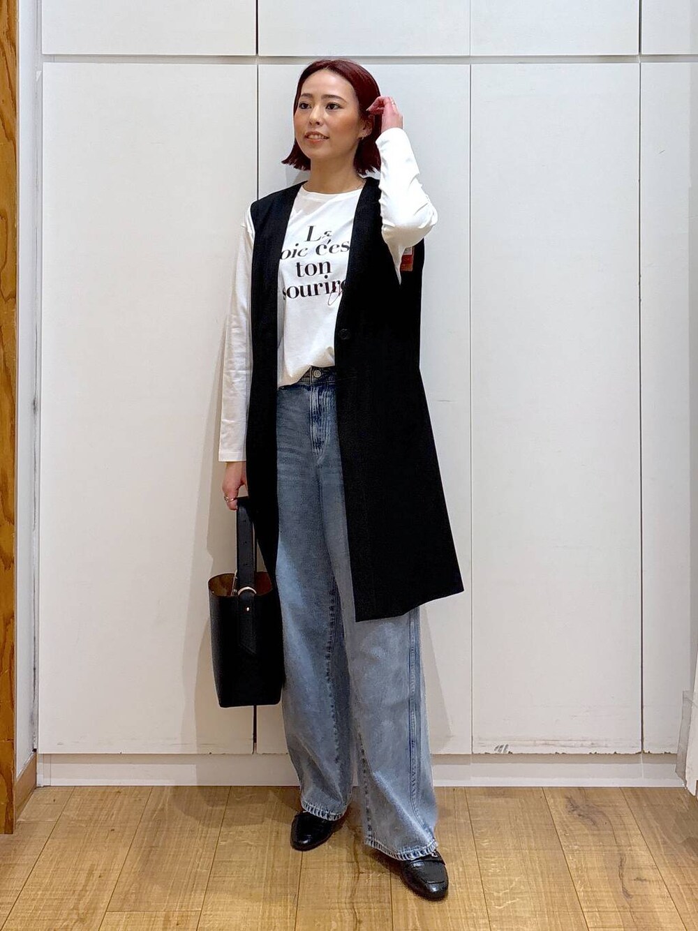 ブルー系のデニムパンツ、ブラック系のローファー、ブラック系のベストを着用したレディースの春コーディネートの1枚目の写真