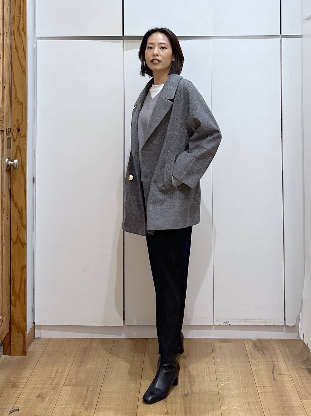 グレー系のチェスターコート、ブラック系のその他パンツ、グレー系のニット/セーターを着用したレディースの秋コーディネートの1枚目の写真