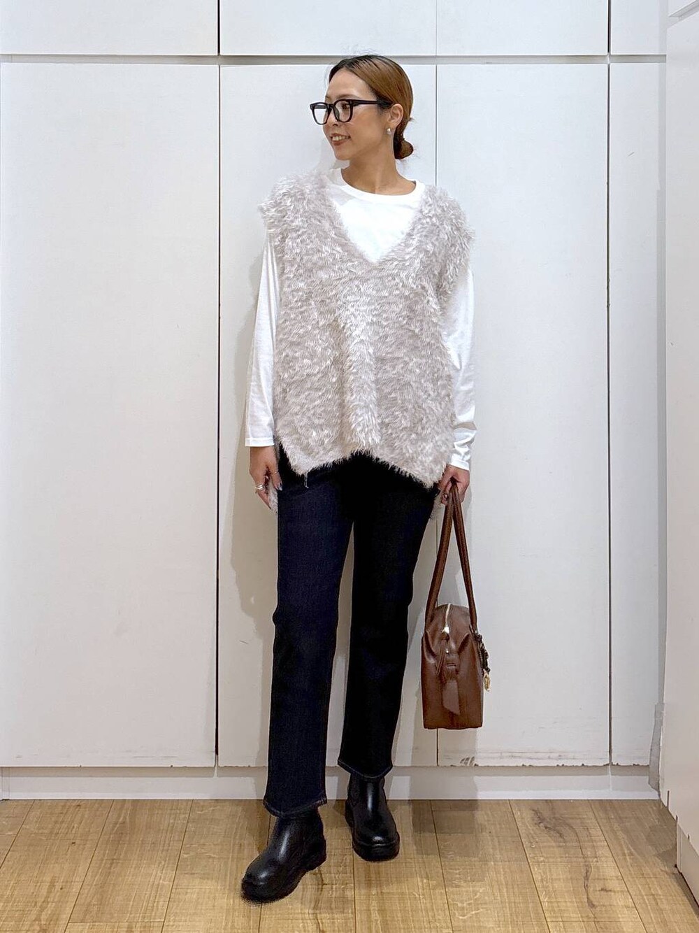 ブラウン系のボストンバッグ、ブルー系のデニムパンツ、ホワイト系のTシャツ/カットソーを着用したレディースの秋コーディネートの1枚目の写真