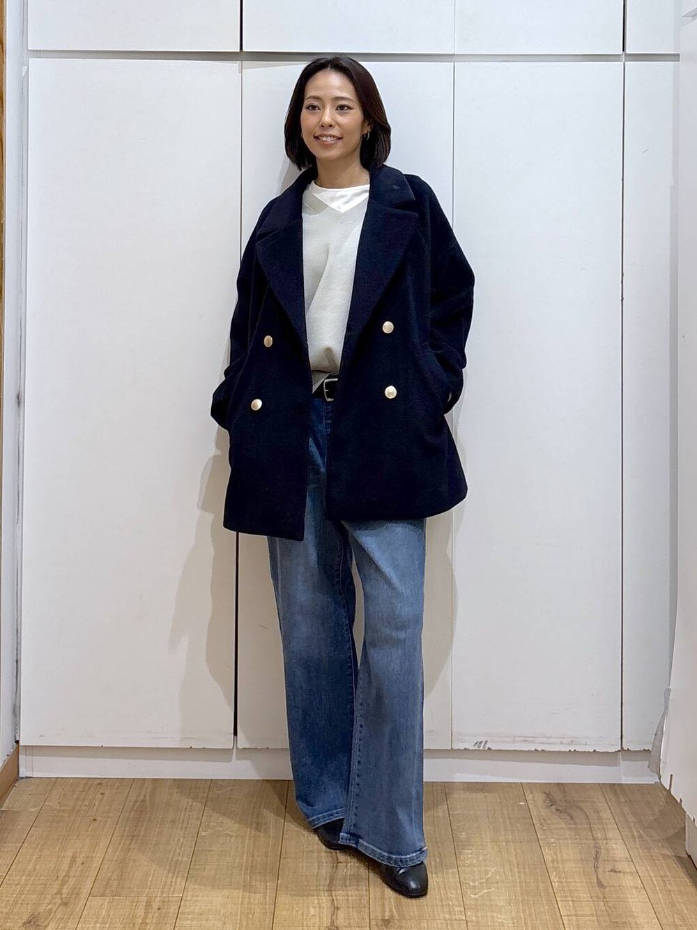 ブルー系のチェスターコート、ベージュ系のスウェット、ブラック系のブーツを着用したレディースの秋コーディネートの1枚目の写真