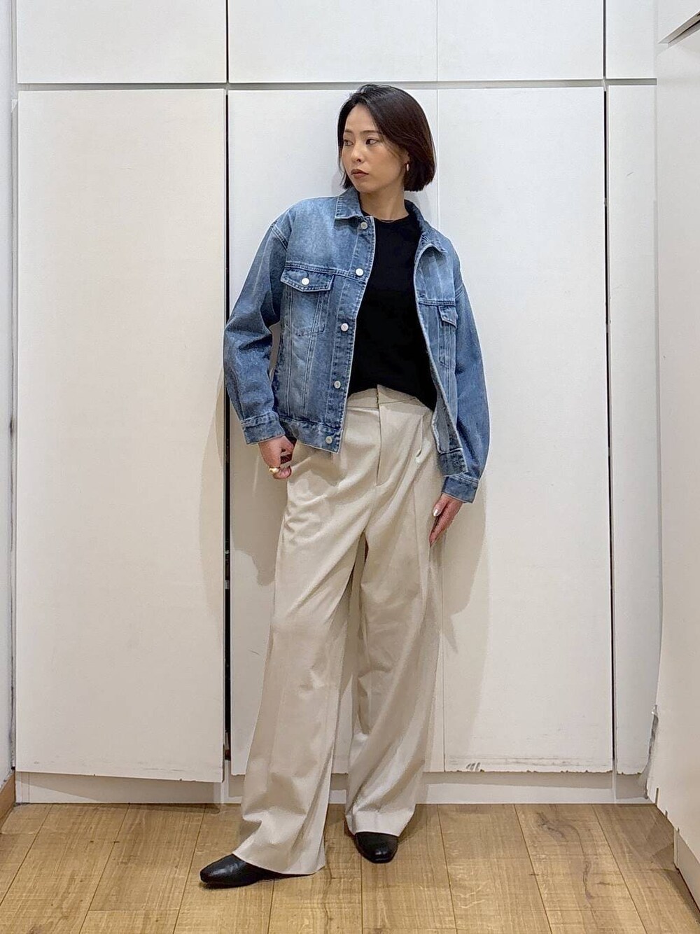 ベージュ系のスラックス、ブラック系のブーツ、ブルー系のデニムジャケットを着用したレディースの冬コーディネートの1枚目の写真