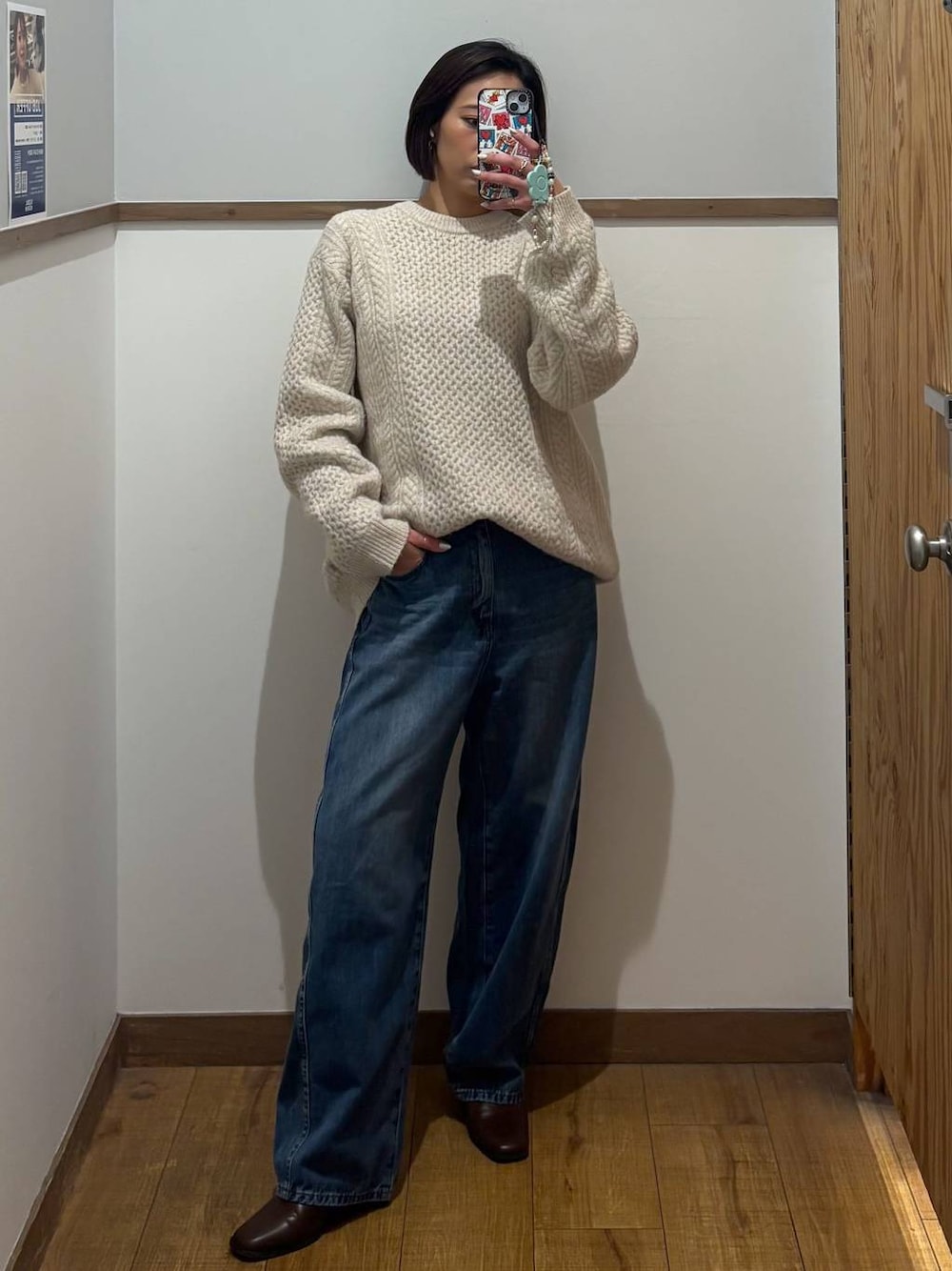 ブラウン系のブーツ、ホワイト系のニット/セーター、ブルー系のデニムパンツを着用したレディースの冬コーディネートの1枚目の写真