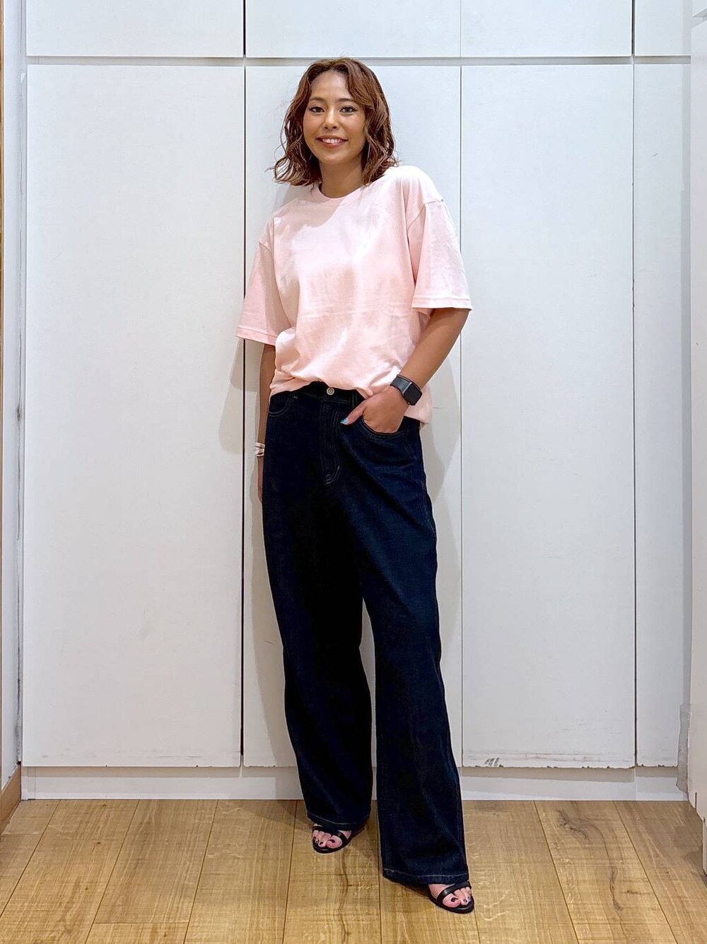 ブルー系のデニムパンツ、ピンク系のTシャツ/カットソー、ブラック系のサンダルを着用したレディースの夏コーディネートの1枚目の写真