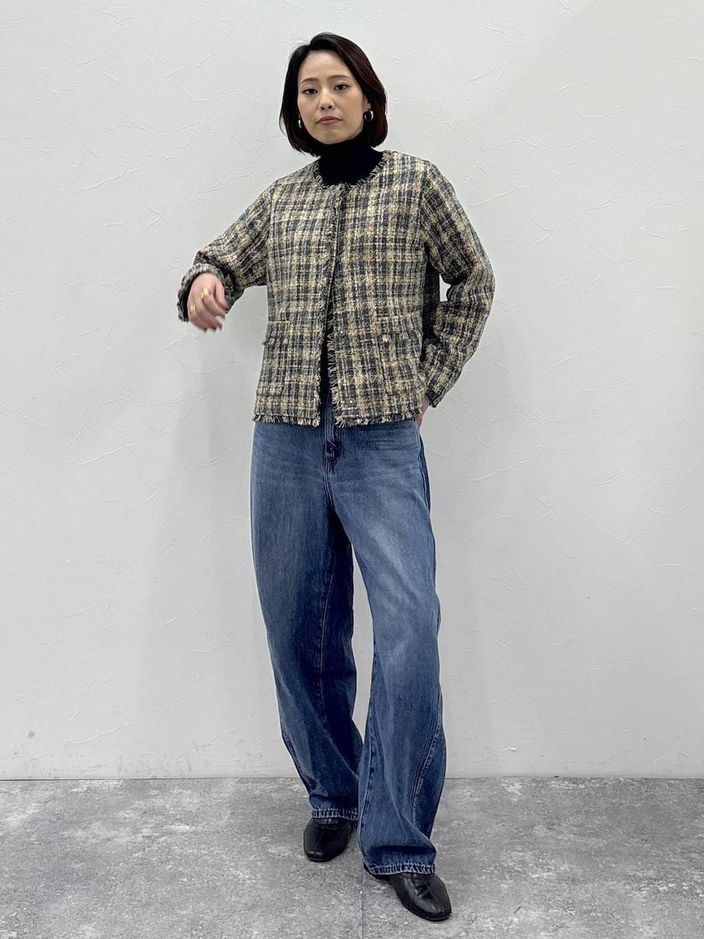 ブラック系のニット/セーター、ブラック系のブーツ、ブルー系のデニムパンツを着用したレディースの冬コーディネートの1枚目の写真