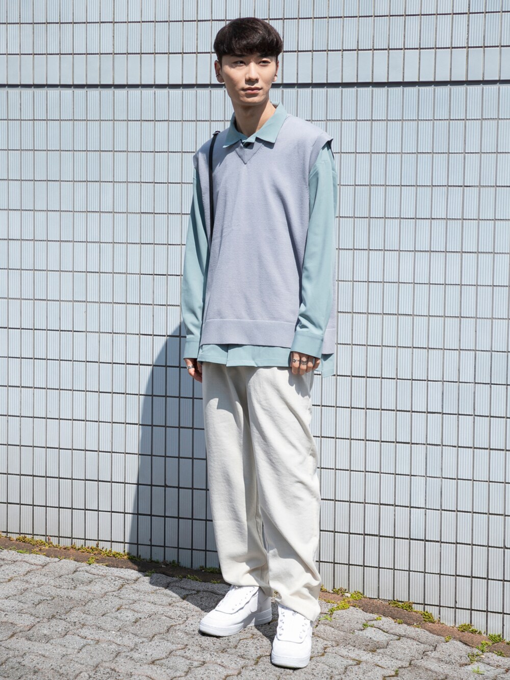 ホワイト系のスニーカー、ホワイト系のスラックス、ブルー系のベストを着用したメンズの春コーディネートの1枚目の写真