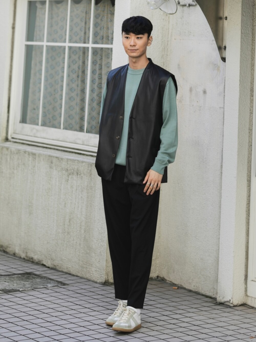 ホワイト系のスニーカー、ブラック系のスラックス、ブラック系のベストを着用したメンズの秋コーディネートの1枚目の写真
