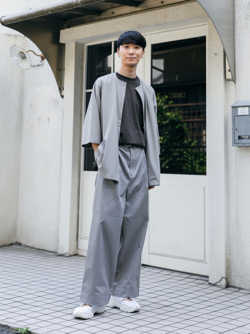 ホワイト系のスニーカー、グレー系のチノパンツ、グレー系のTシャツ/カットソーを着用したメンズの夏コーディネートの1枚目の写真