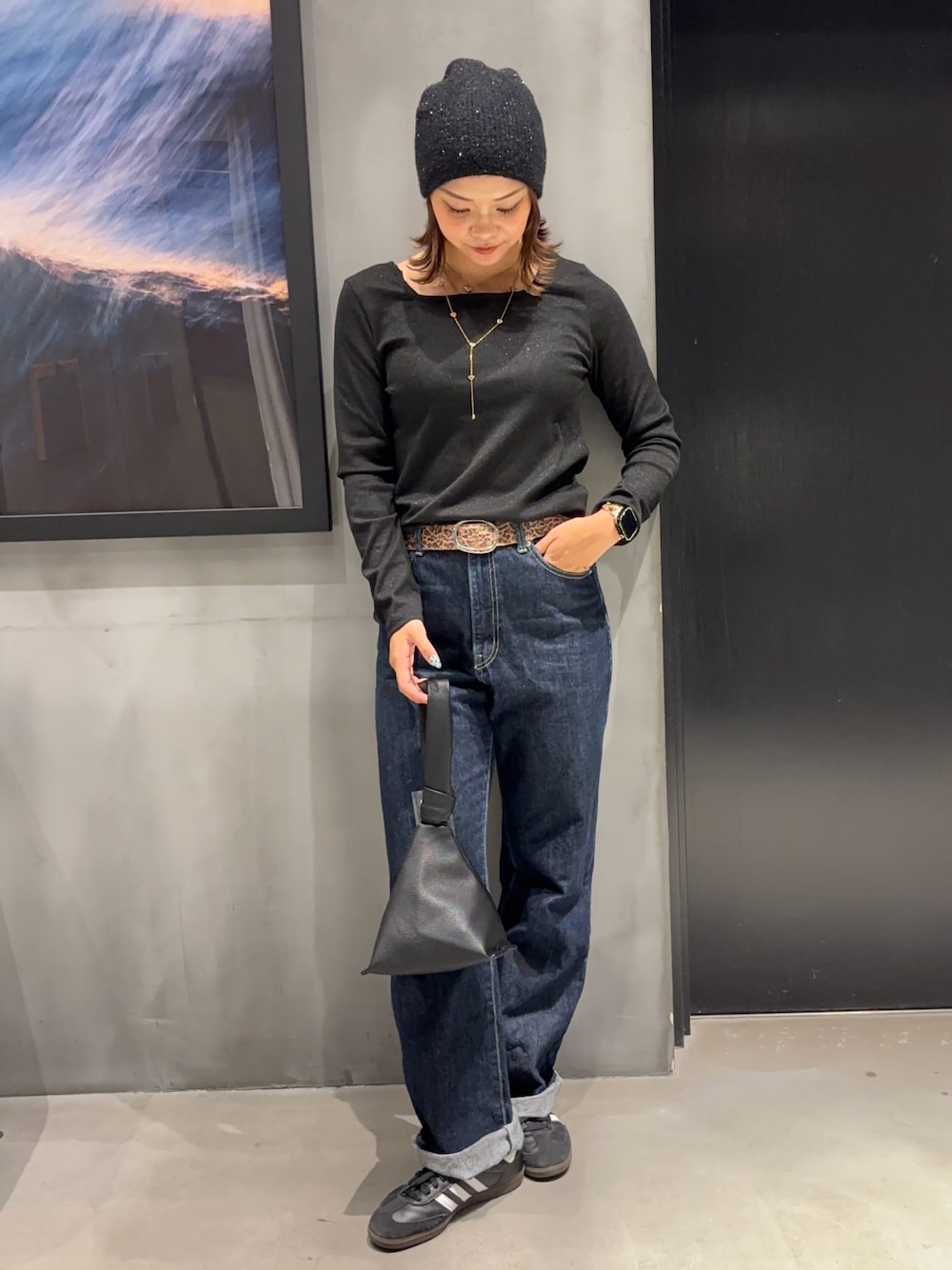 ブルー系のデニムパンツ、ブラック系のハンドバッグ、ブラック系のTシャツ/カットソーを着用したレディースの秋コーディネートの1枚目の写真