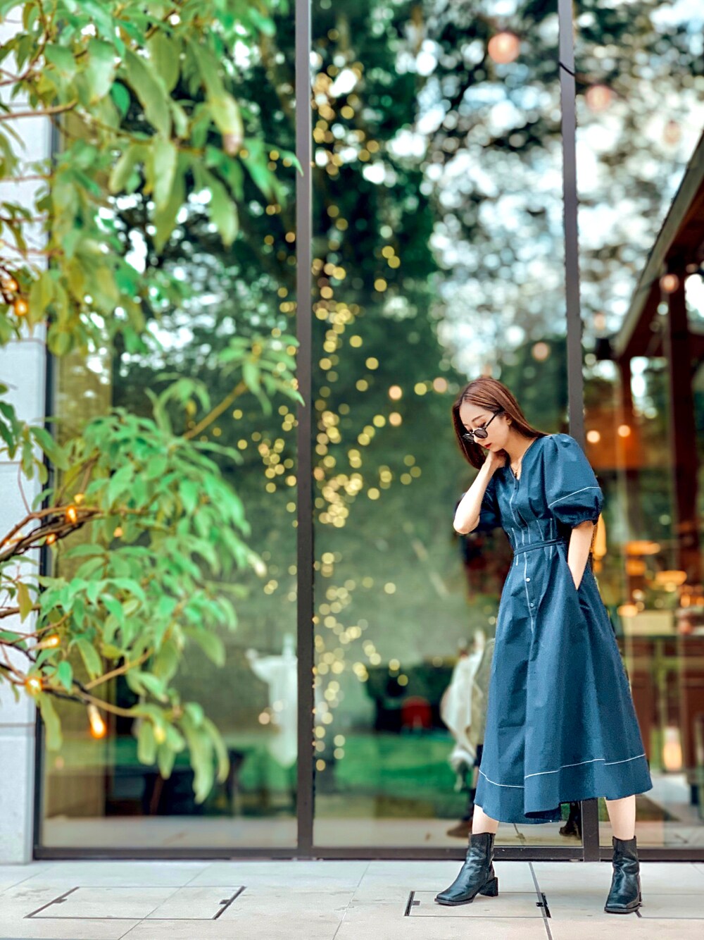 ブルー系のワンピース、ブラック系のブーツ、ブラック系のサングラスを着用したレディースの秋コーディネートの1枚目の写真