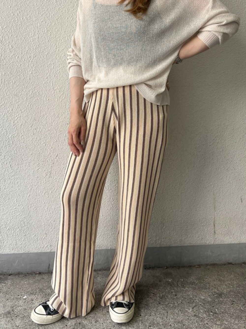 ベージュ系のその他パンツ、ホワイト系のニット/セーター、ブラック系のスニーカーを着用したレディースの夏コーディネートの1枚目の写真