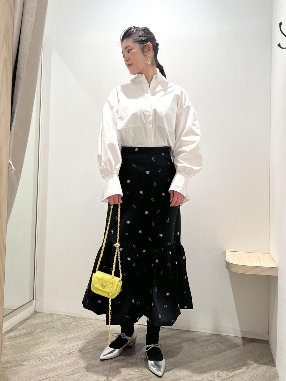 シルバー系のパンプス、イエロー系のショルダーバッグ、ブラック系のスカートを着用したレディースの冬コーディネートの1枚目の写真