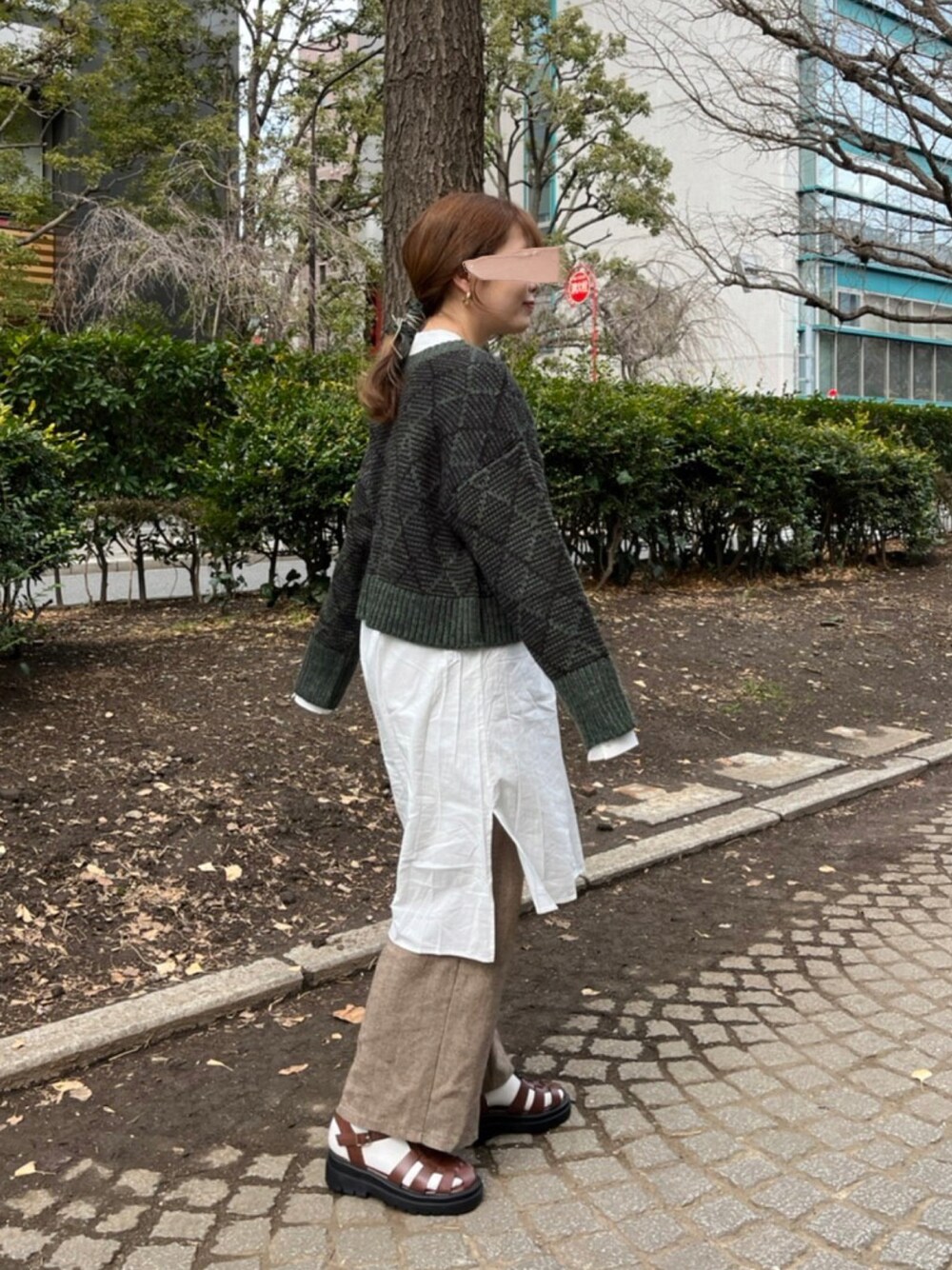 グリーン系のニット/セーター、ホワイト系のシャツ/ブラウス、ブラウン系のサンダルを着用したレディースの冬コーディネートの1枚目の写真