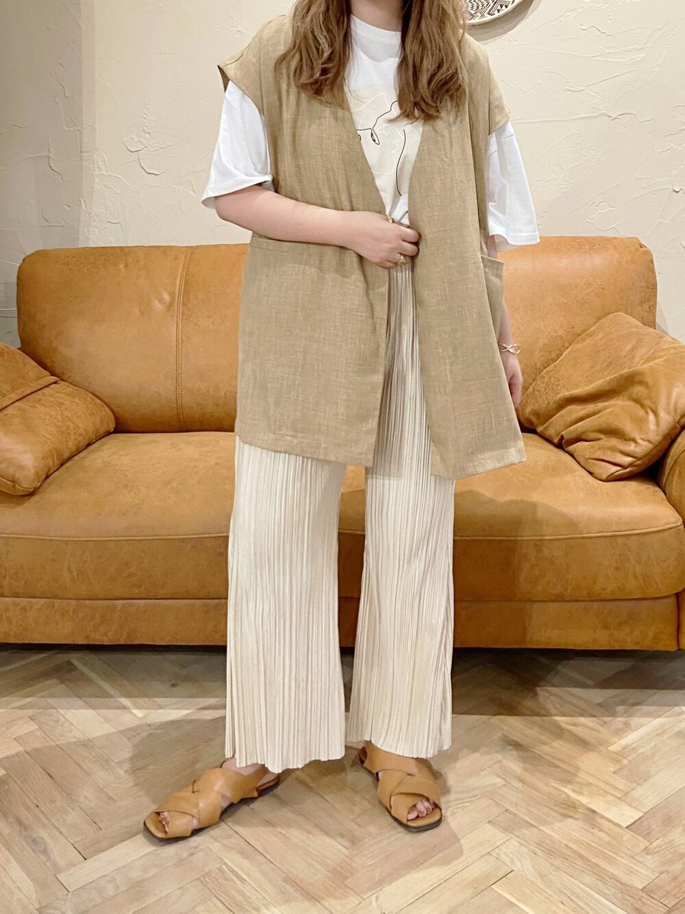 ベージュ系のベスト、ホワイト系のその他パンツ、ブラウン系のサンダルを着用したレディースの夏コーディネートの1枚目の写真