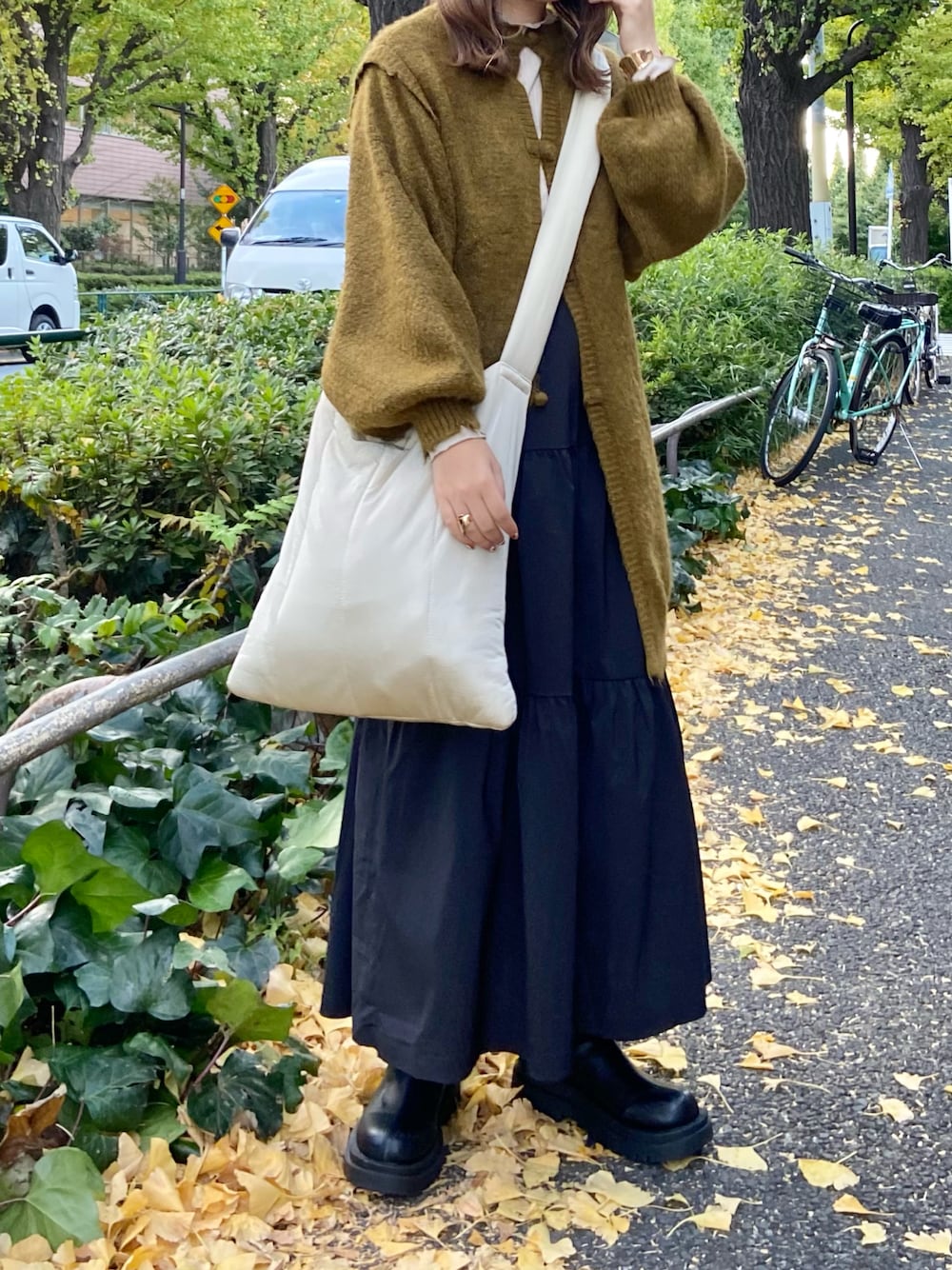 グリーン系のニット/セーター、ブラック系のスカート、ブラック系のブーツを着用したレディースの冬コーディネートの1枚目の写真