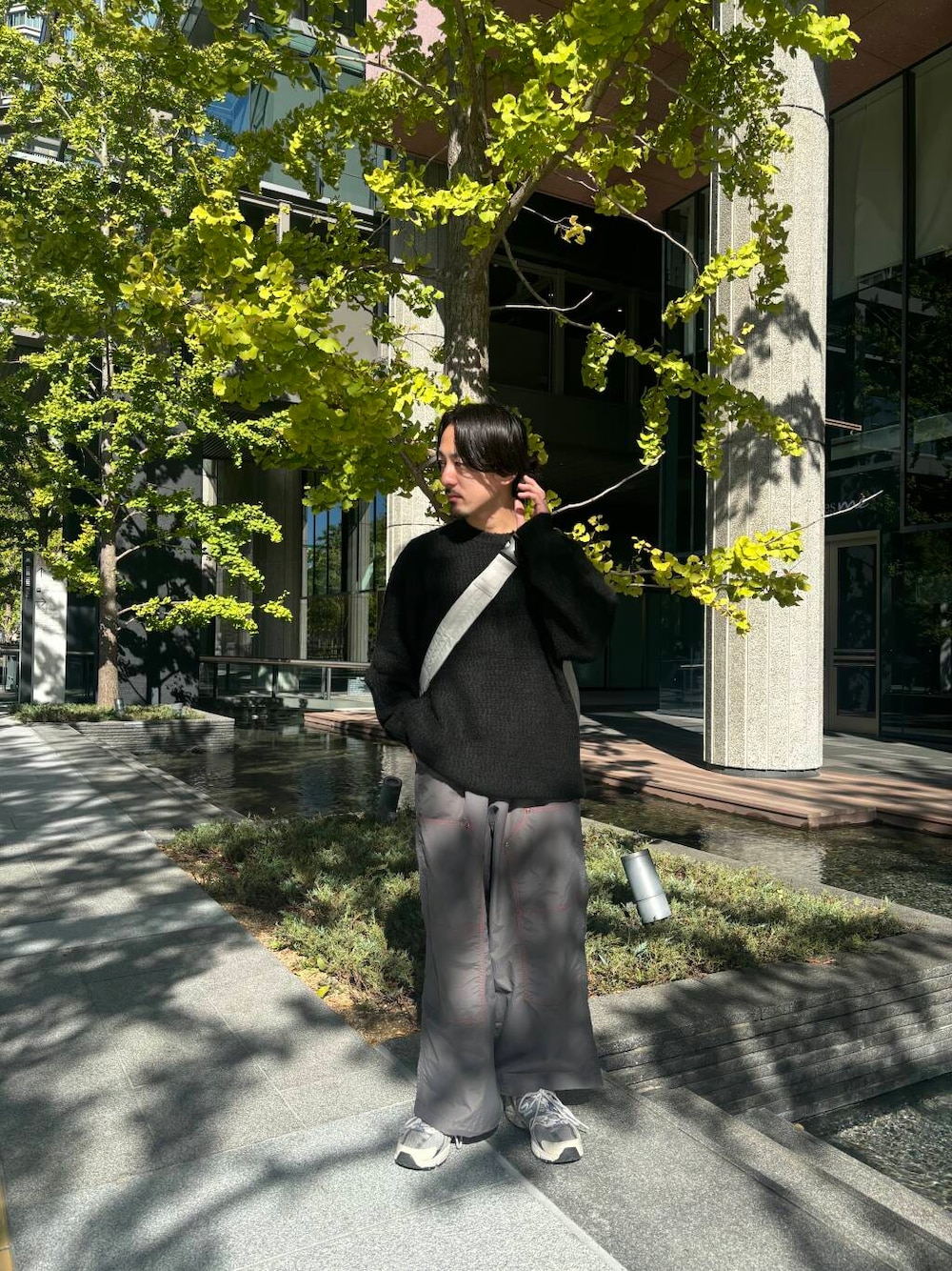 グレー系のショルダーバッグ、グレー系のその他パンツ、ブラック系のニット/セーターを着用したメンズの秋コーディネートの1枚目の写真