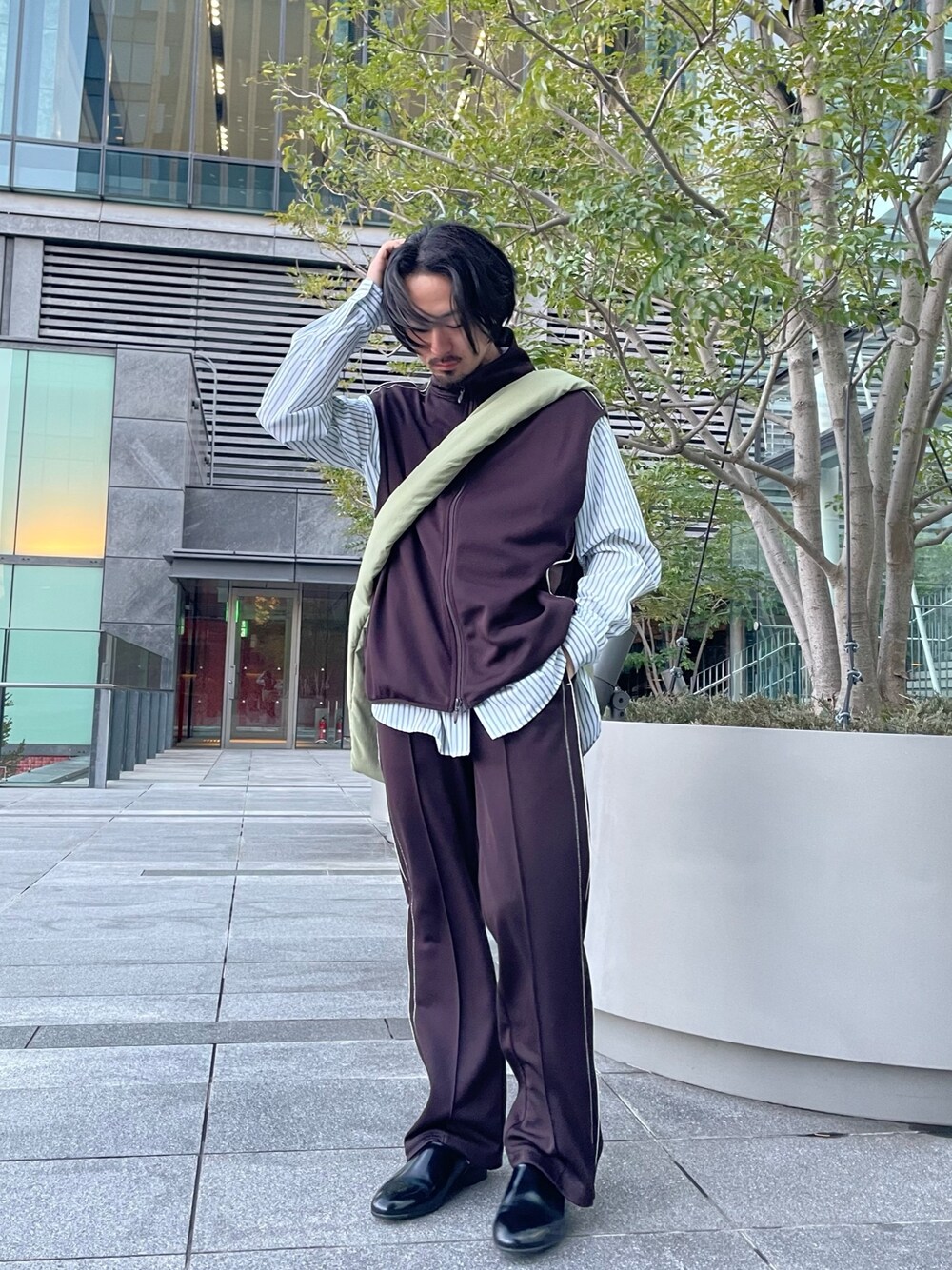 ブラウン系のその他パンツ、ブラウン系のベスト、グリーン系のショルダーバッグを着用したメンズの春コーディネートの1枚目の写真